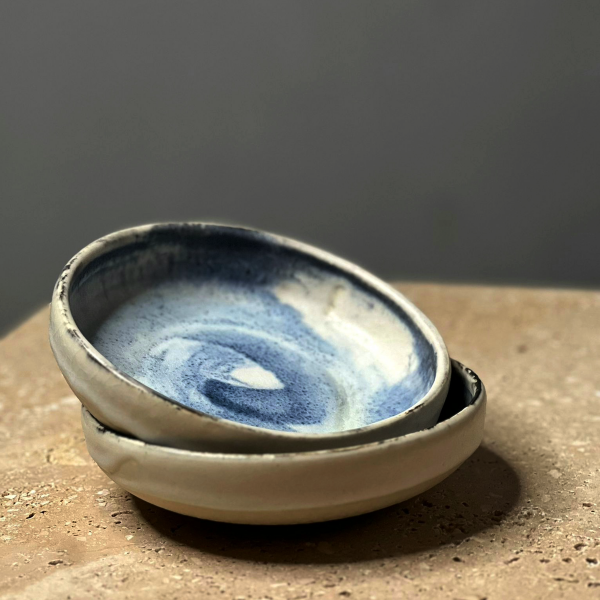 Stoneware with Blue Glaze Finish This stunning set of handcrafted ceramic bowls by Kyu embodies the perfect fusion of artistry and functionality. The soft, organic forms and unique blue glaze evoke the calming beauty of natural landscapes, creating a serene and sophisticated aesthetic. Each bowl is a testament to Kyu's mastery in ceramics, showcasing the subtle imperfections that celebrate the charm of handmade craftsmanship. Ideal for both everyday use and decorative purposes, these bowls bring a touch of artistry to any space. This is an original handmade set, ensuring that no two pieces are exactly alike, making it a truly unique addition to your collection.